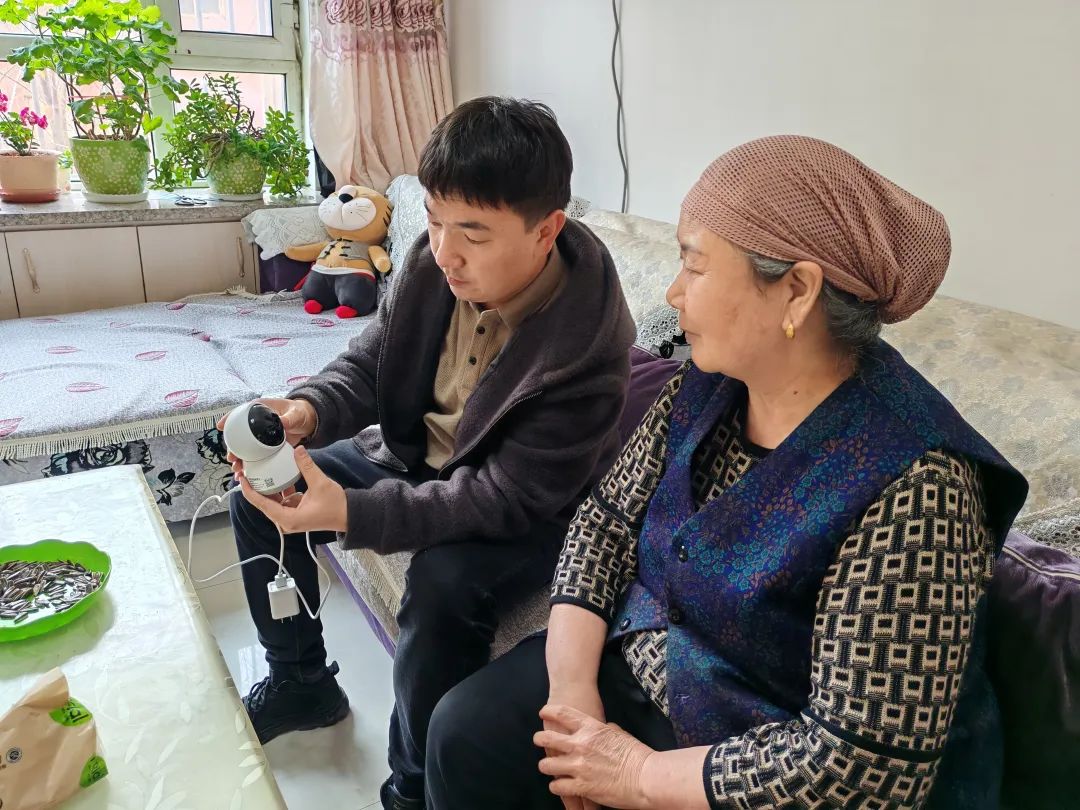 图为十二师残联工作人员为残疾人家庭成员讲解如何使用智能摄像头